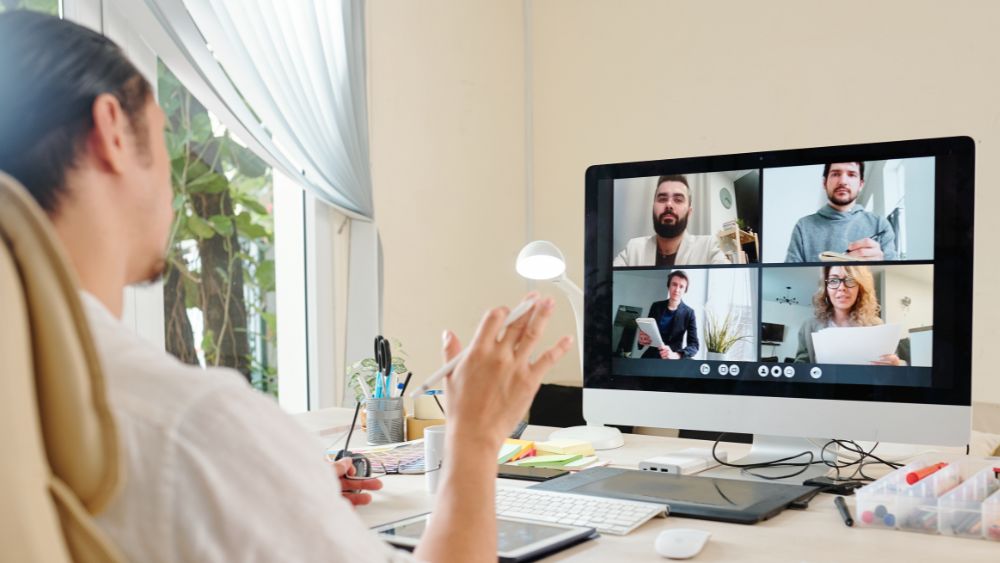 Man participating in an online meeting at his home with 4 other participants
