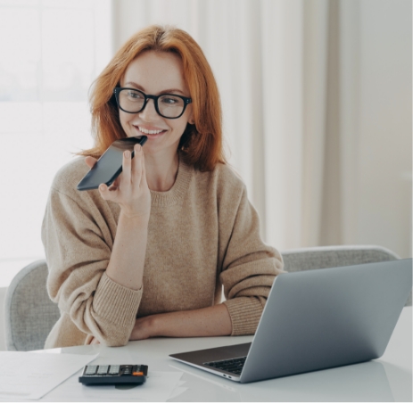 ginger woman dictating to her phone happily usin speech-to-text API